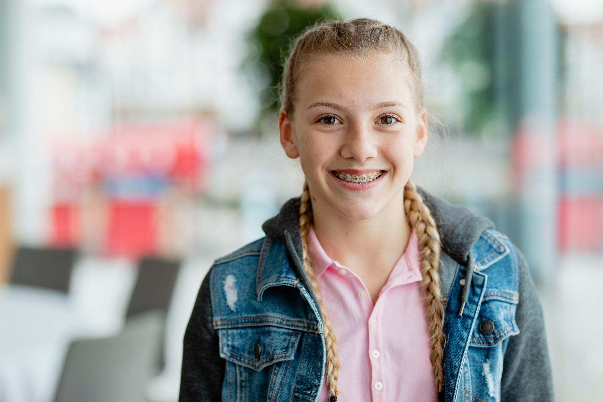 Smiling girl with braided blonde hair shows off a healthy, confident smile after care with Dr. Matthew Noyce, orthodontist in Maryville, MO at Noyce Orthodontics